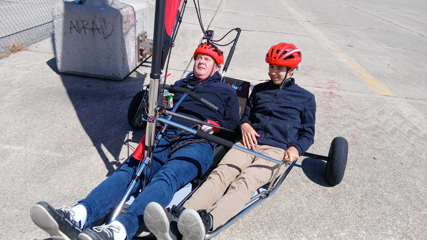 Two riders in helmets reclined in a sail kart