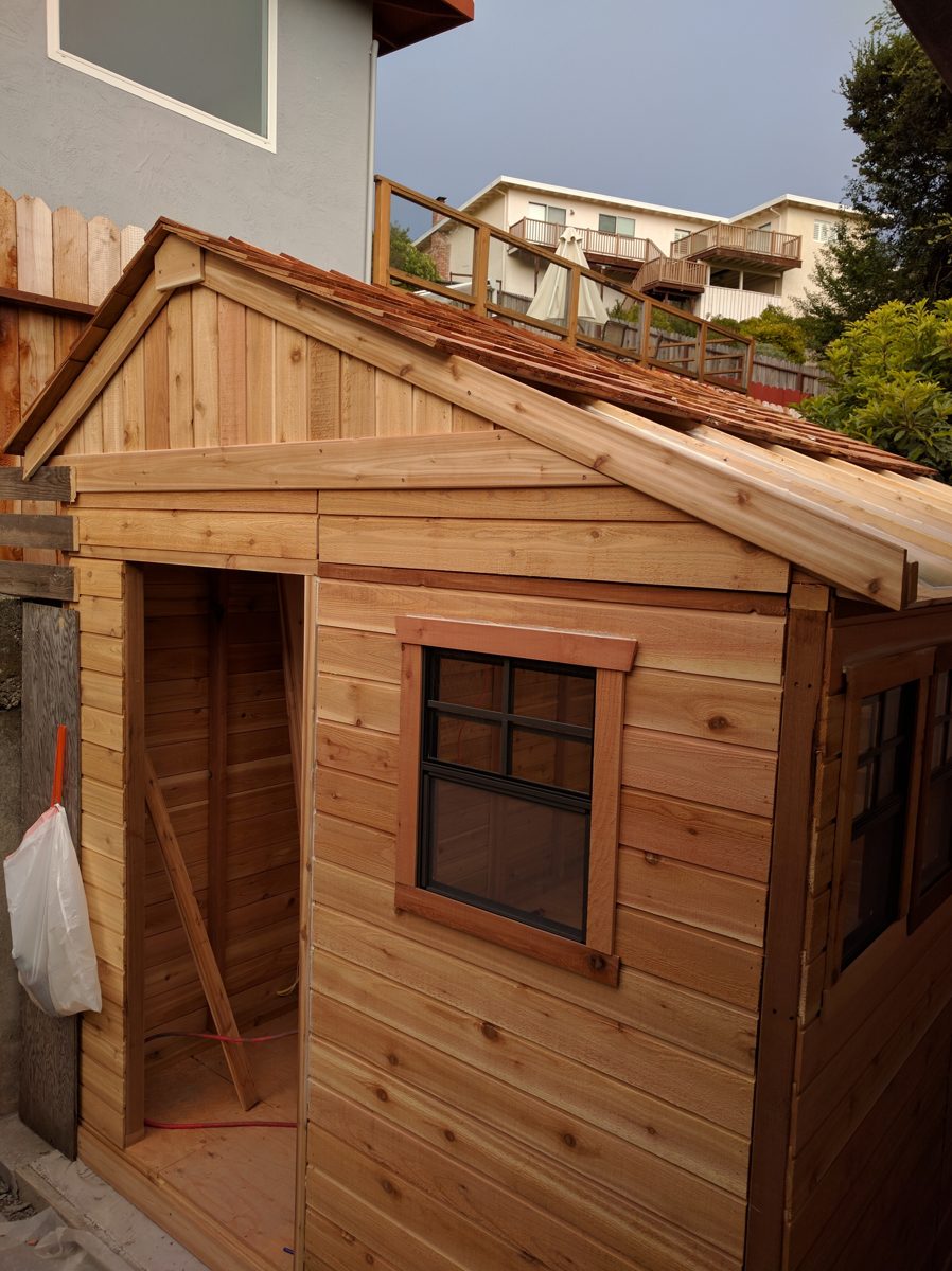 The shed under construction in July 2018: a cedar shed with a gabled roof and a small window
